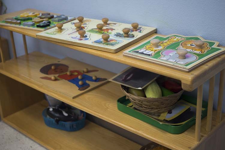 A low Montessori shelf of jigsaw puzzles set out for little hands