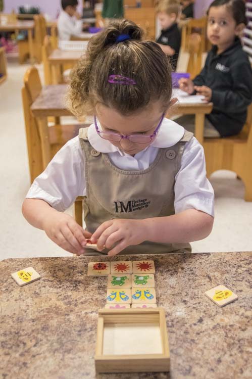 A child working through one of the Montessori lessons at a low table